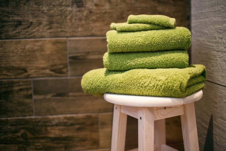 five lime green towels ready on a guest bathroom stool