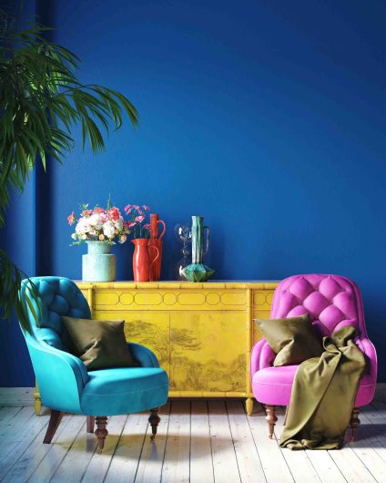 a room decorated with a blue colour on the walls and pink and turquoise chairs in front of a yellow sideboard