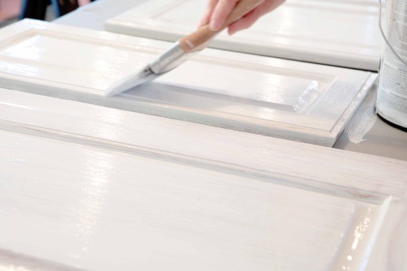 a person trying to update a kitchen by painting Shaker kitchen cupboards in white paint