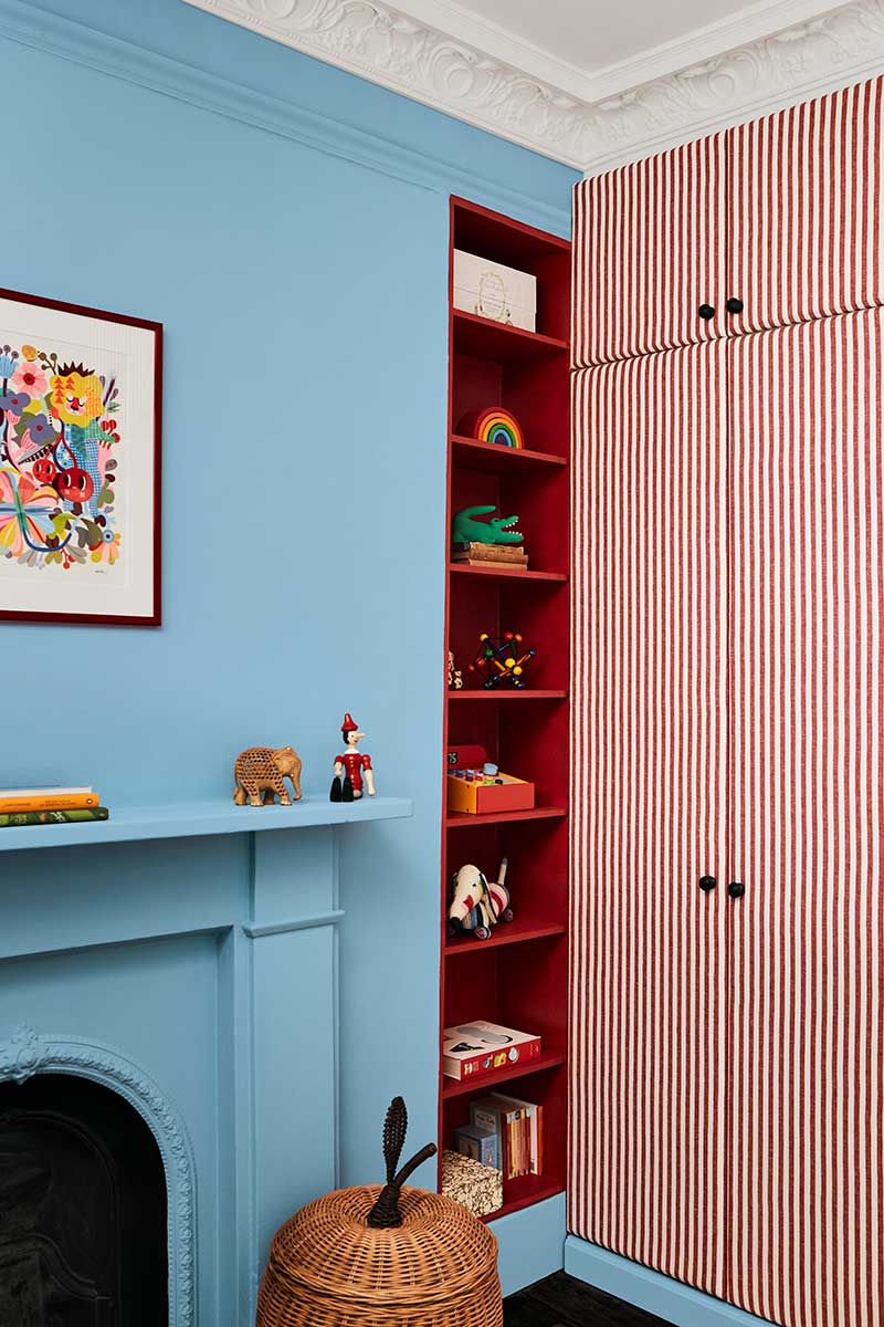 A wall painted in baby blue, with a striped cabinet on the right