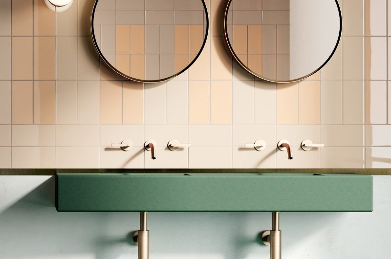 Pared-back bathroom with green concrete sink, gold brassware, two round mirrors and metro tiles